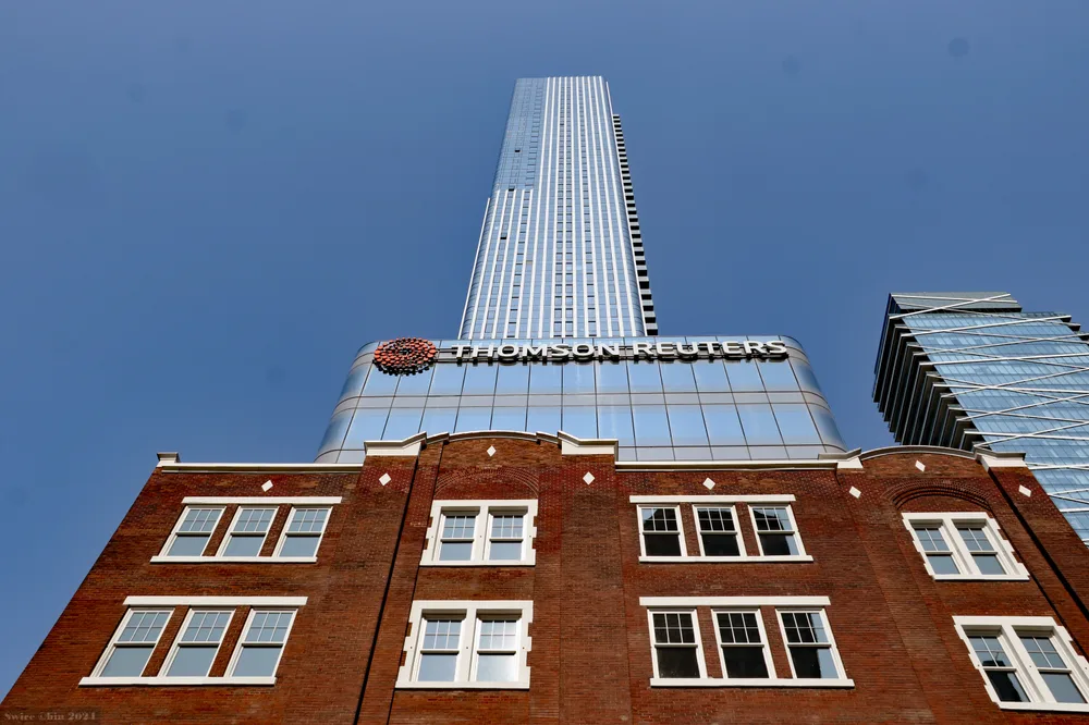 A glass tower with a 'Thomson Reuters' sign rising above the red-brick facade of the former Southam Press building.