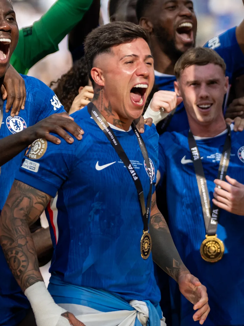Enzo Fernández celebrating with Chelsea teammates, wearing a winner’s medal.