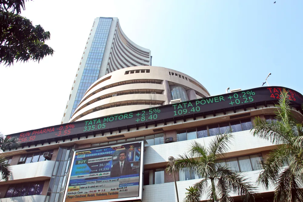 The curved tower of the BSE building in Mumbai, with an electronic share-price ticker showing Tata Motors and Tata Power across its lower floors.