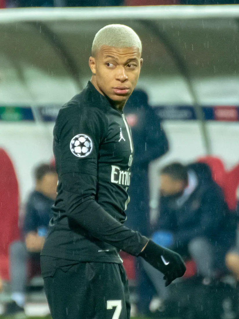 Kylian Mbappé in a black Paris Saint-Germain kit on the pitch.