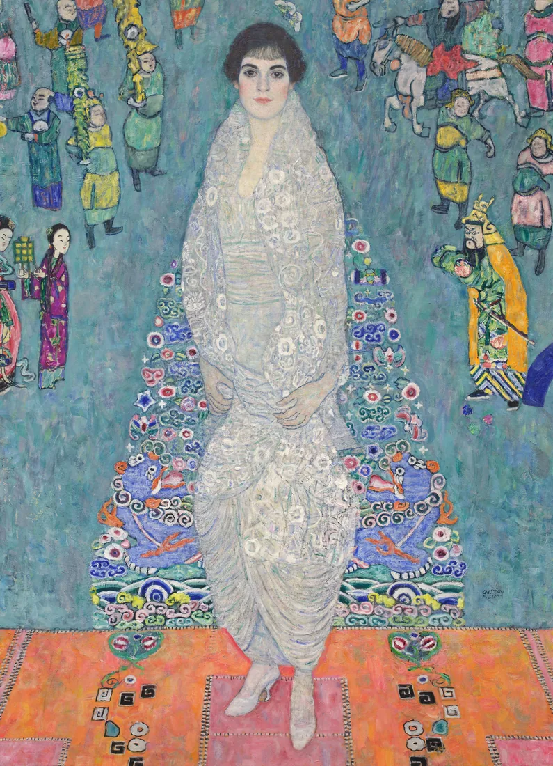 A young woman in a white dress and shawl standing on a patterned carpet.