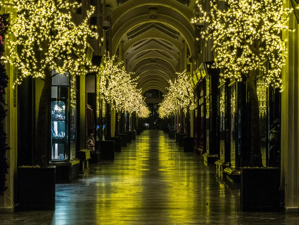 The empty, vaulted interior of Burlington Arcade lit by trees strung with white lights.