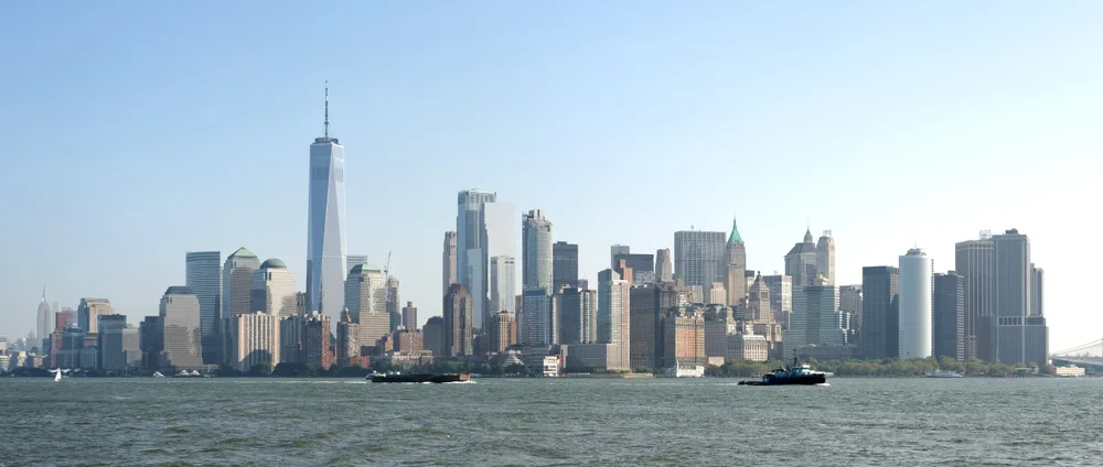 Skyscrapers of a city's financial district seen across open water on a clear day.